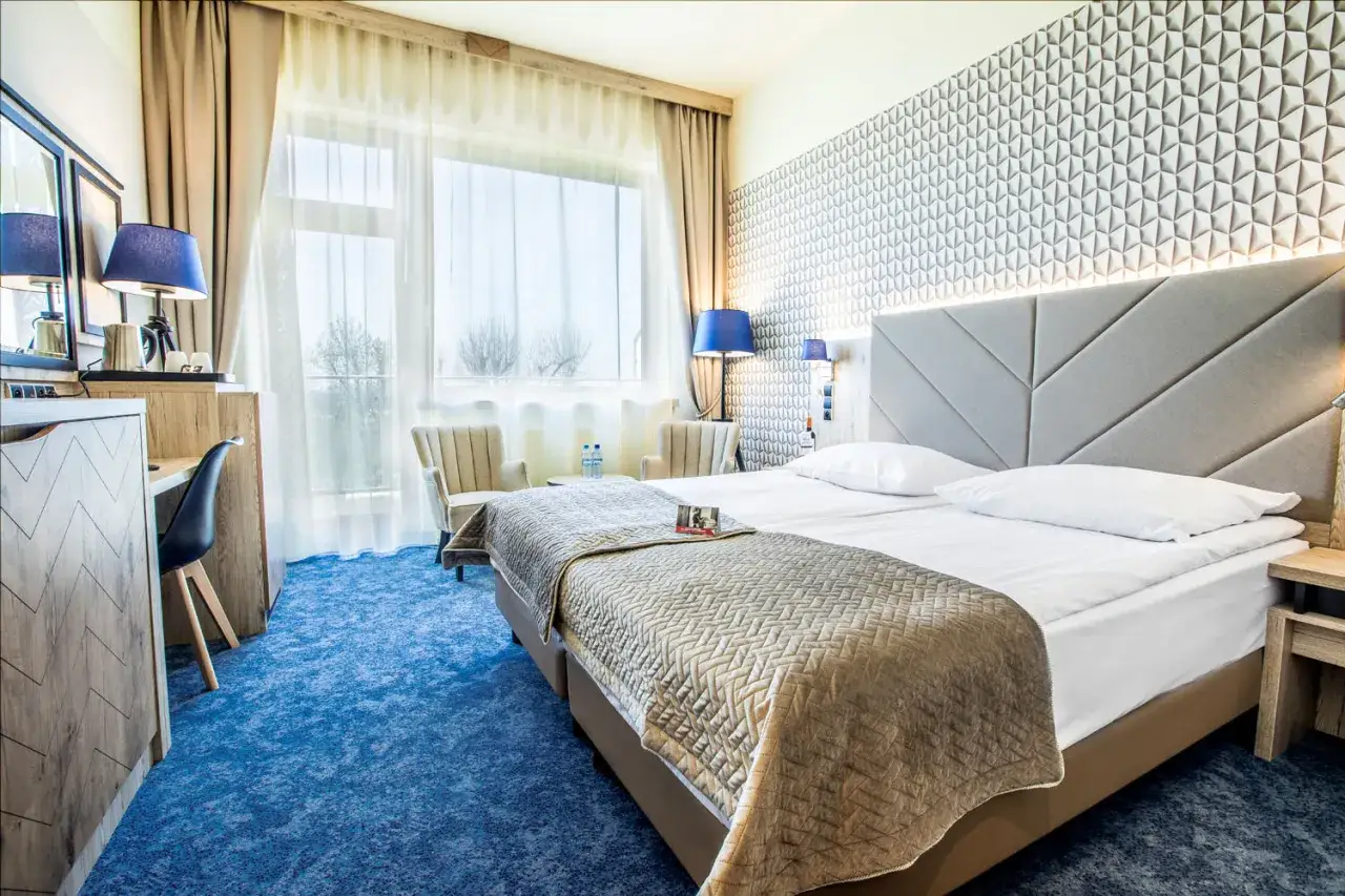 Pokój w hotelu Diament Ustroń. Wygodne łóżko, stylowe meble i duży balkon. Idealne miejsce na relaks, zgodnie z opiniami o spa & wellness hotel diament ustroń opinie.