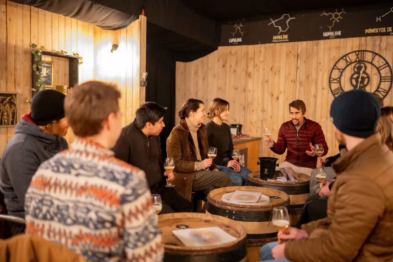 Un groupe d'amis profite d'une d&eacute;gustation, un accord met bi&egrave;re est en cours. Ils sont assis autour de tonneaux en bois, chacun tenant un verre de bi&egrave;re.