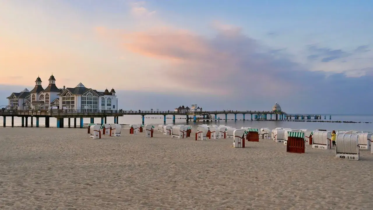Strandkörbe am Sandstrand vor einer Seebrücke mit historischem Gebäude. Perfekt für einen Urlaub in Norddeutschland.