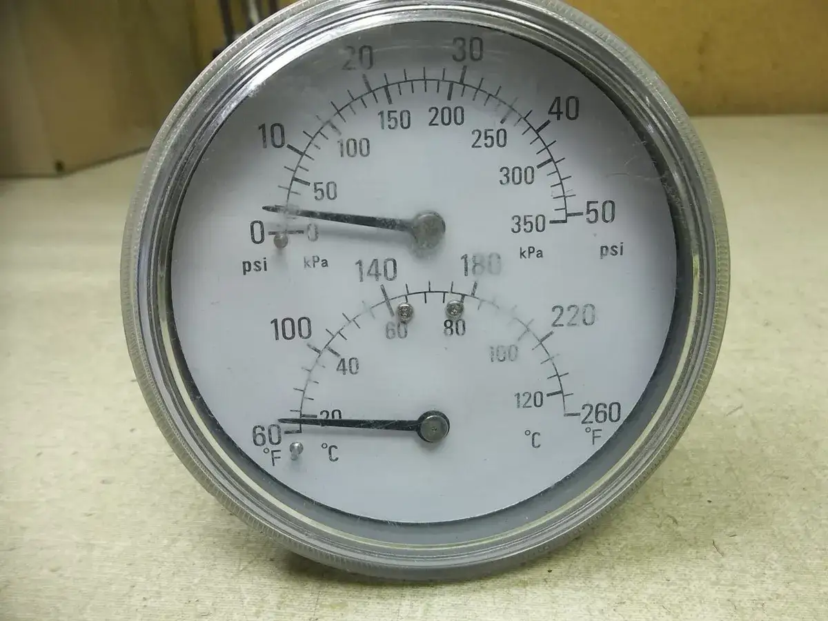 Man&oacute;metro con escalas de presi&oacute;n (psi, kPa) y temperatura (&deg;C, &deg;F). La aguja de presi&oacute;n marca cerca de 0 psi, indicando que es psi.