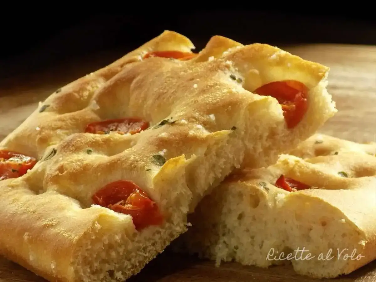 Focaccia alta e soffice con pomodorini e sale grosso, un morso invitante.