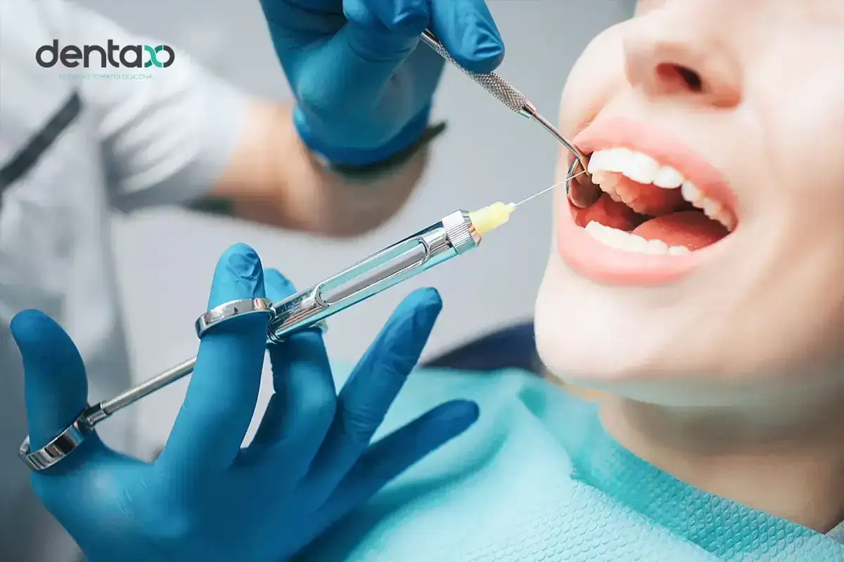 Dentysta wykonuje znieczulenie śródwięzadłowe, podając środek znieczulający do jamy ustnej pacjenta.