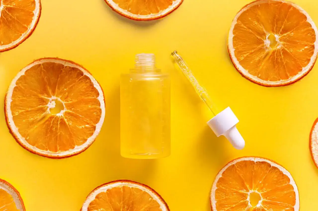 Ein Fl&auml;schchen mit gelbem Serum und Pipette, umgeben von getrockneten Orangenscheiben. Nat&uuml;rliche Pflege mit Zitronens&auml;ure.