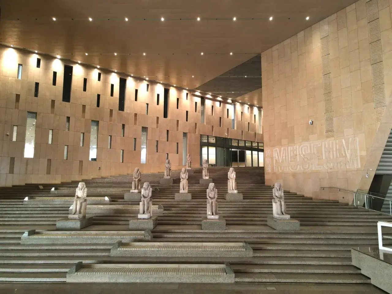 Monumentalne schody prowadzą do nowego muzeum w Egipcie, gdzie posągi starożytnych postaci strzegą wejścia.