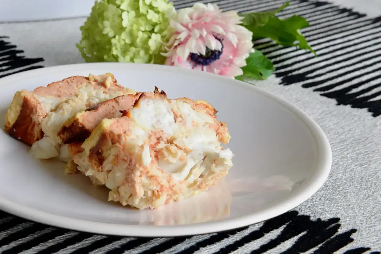Tranches de terrine de lotte savoureuse sur une assiette blanche, accompagn&eacute;es de fleurs d&eacute;licates.
