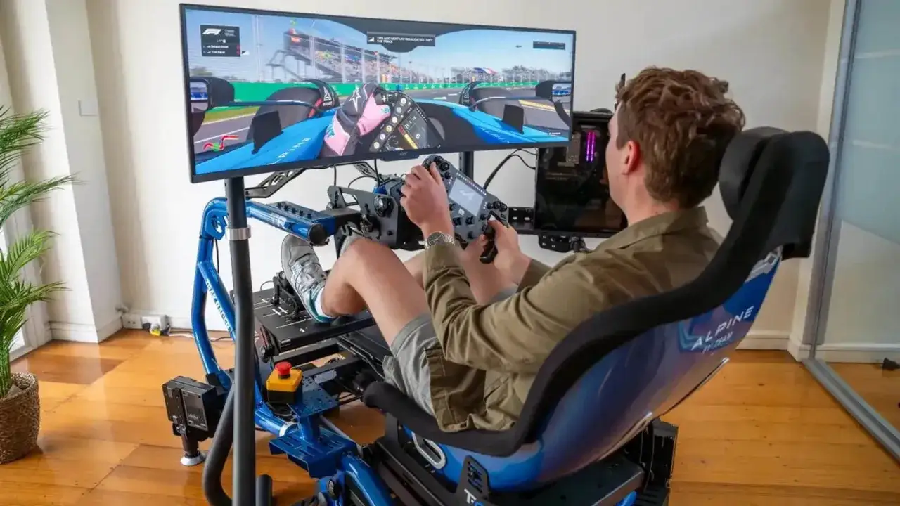 Mężczyzna w fotelu wyścigowym z kierownicą i pedałami, grający w Gran Turismo Sport na wielkim monitorze.