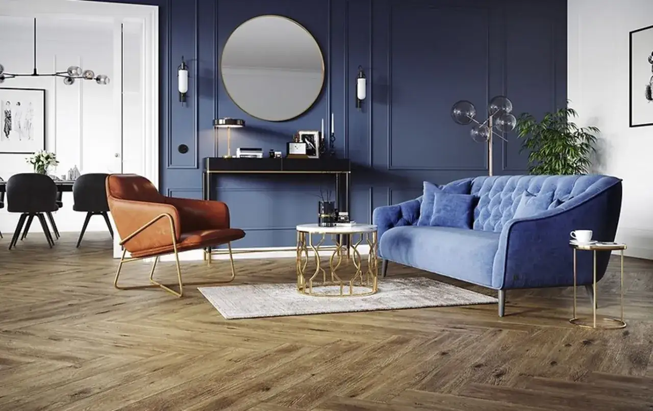 Elegancki granatowy salon inspiracje: aksamitna kanapa, sk&oacute;rzany fotel, okrągłe lustro i złote dodatki tworzą luksusową przestrzeń.