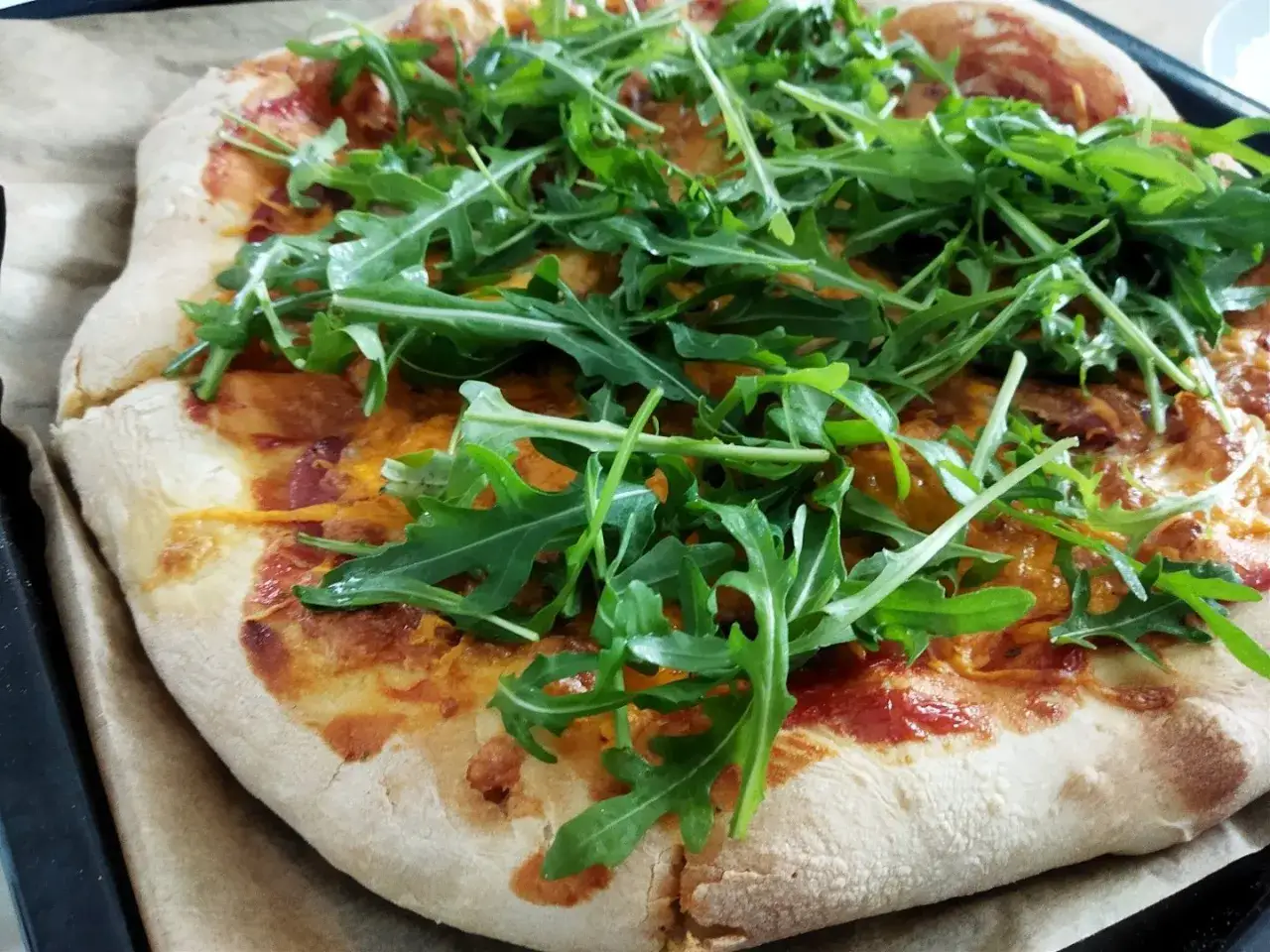 Pizza z salami i rukolą, zapieczona z serem. Idealne dodatki dla miłośników ostrych smaków.