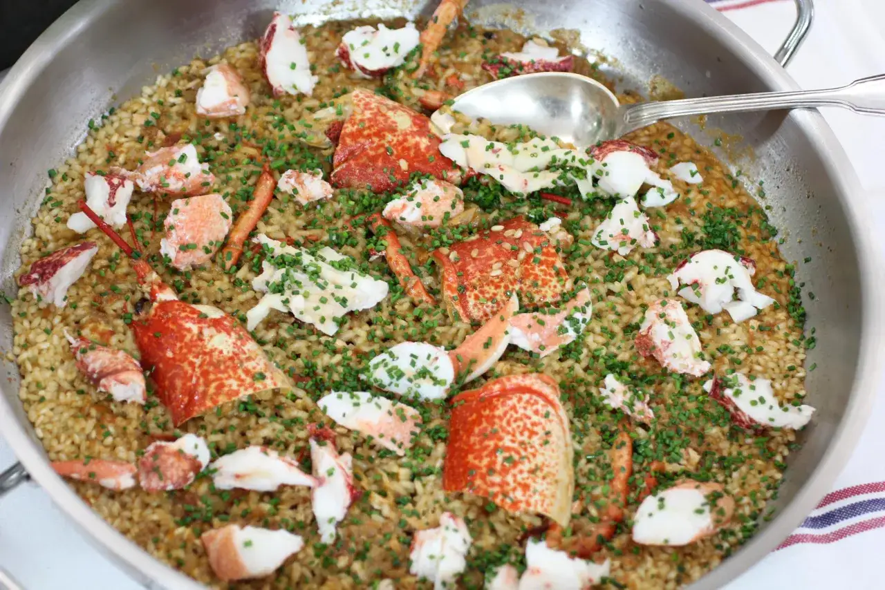 Arroz con bogavante, un plato delicioso con trozos de bogavante fresco y arroz dorado, espolvoreado con cebollino picado.