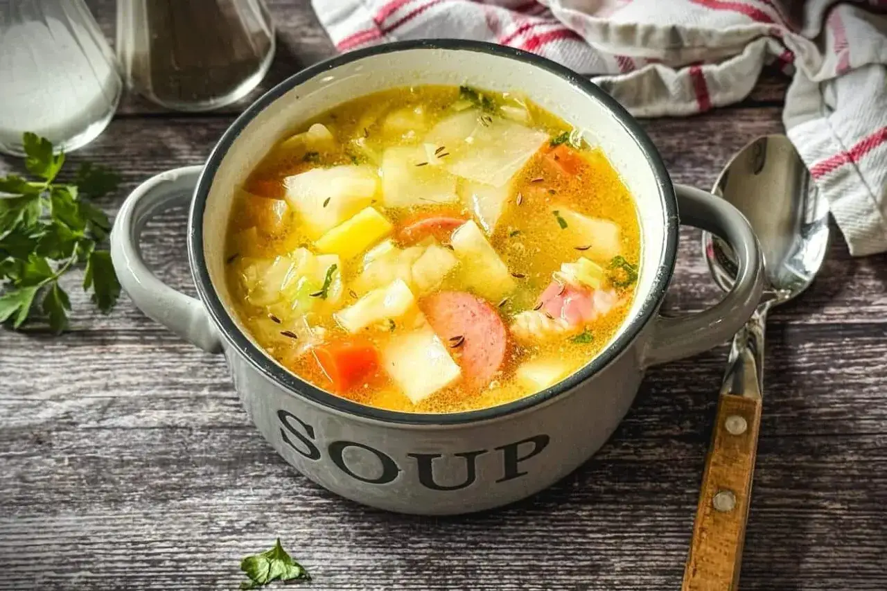 Herzhaftes Kohlsuppe Rezept mit Kartoffeln und Wurst in einer grauen Sch&uuml;ssel, bereit zum Genie&szlig;en.