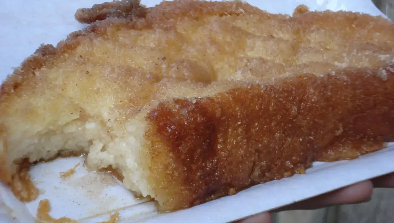 Un trozo de torrija casera, dorada y crujiente por fuera, tierna por dentro, espolvoreada con canela y azúcar. ¡Las mejores torrijas!