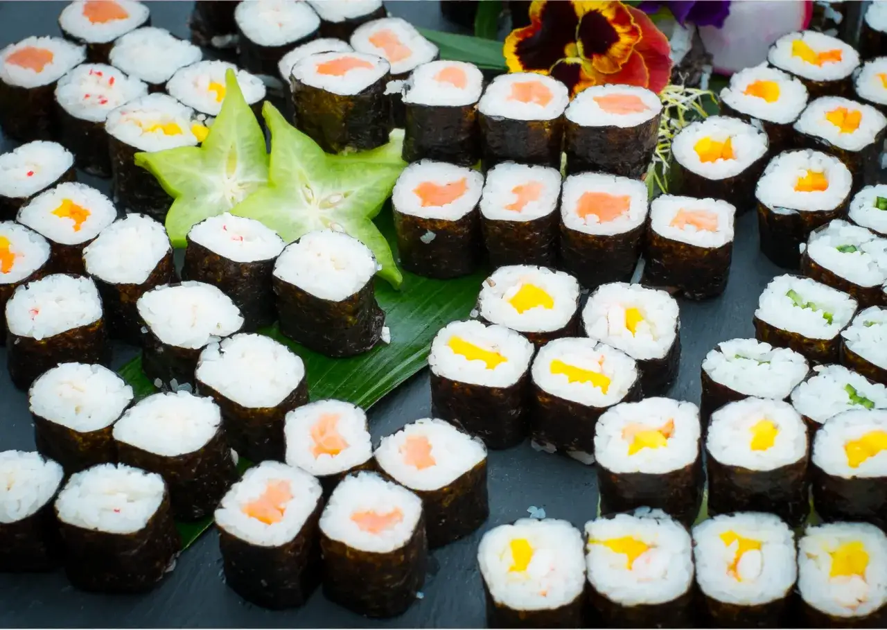 Mnóstwo sushi z łososiem, mango, ogórkiem i krabem. Idealne warzywa do sushi na talerzu.