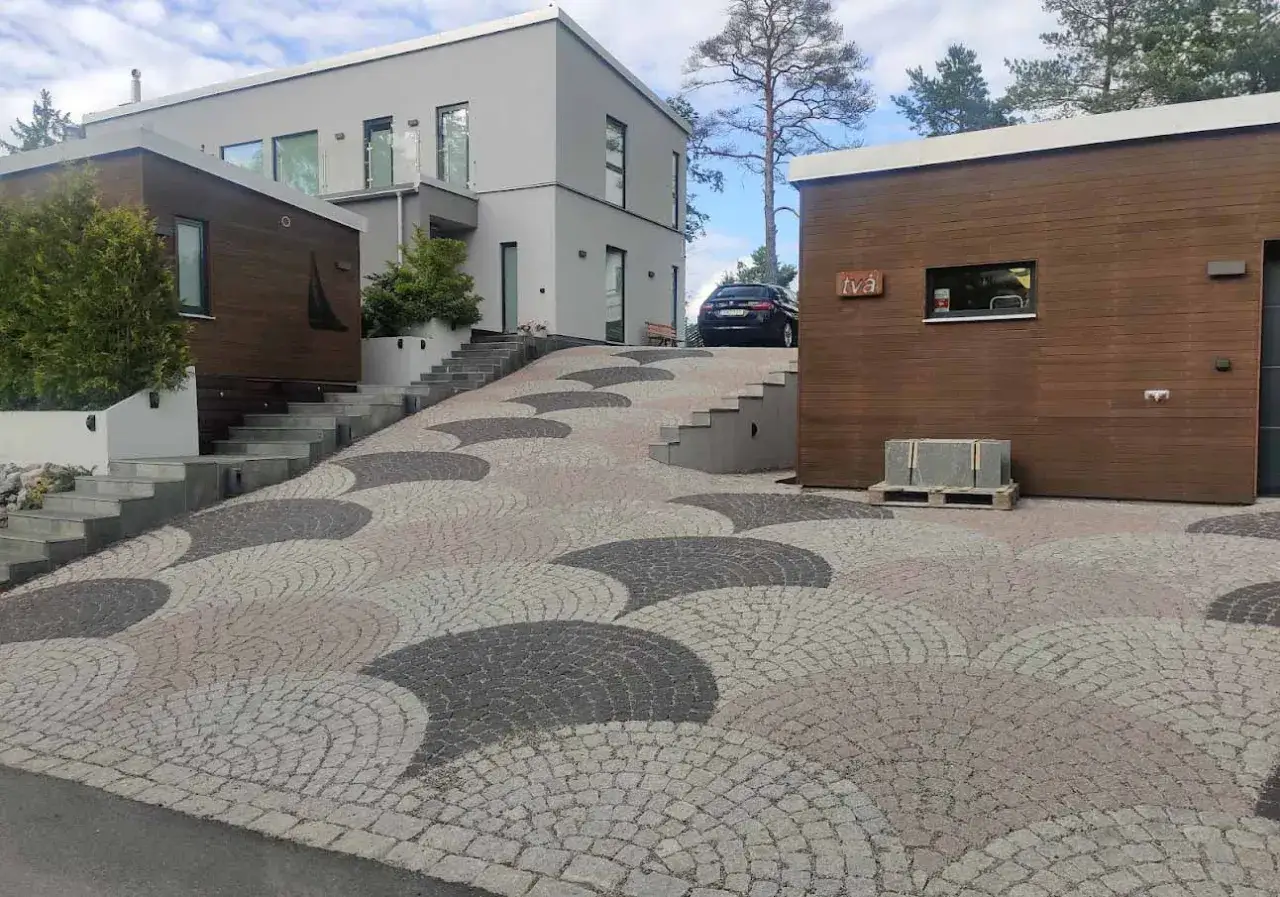 En vacker betong uppfart med ett unikt m&ouml;nster leder upp till ett modernt hus och ett garage.