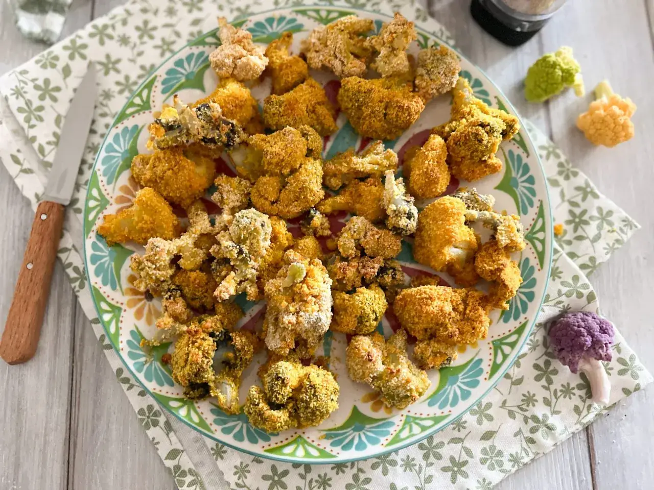 Cavolfiore al forno con pangrattato e formaggio, croccante e dorato, servito su un piatto colorato.