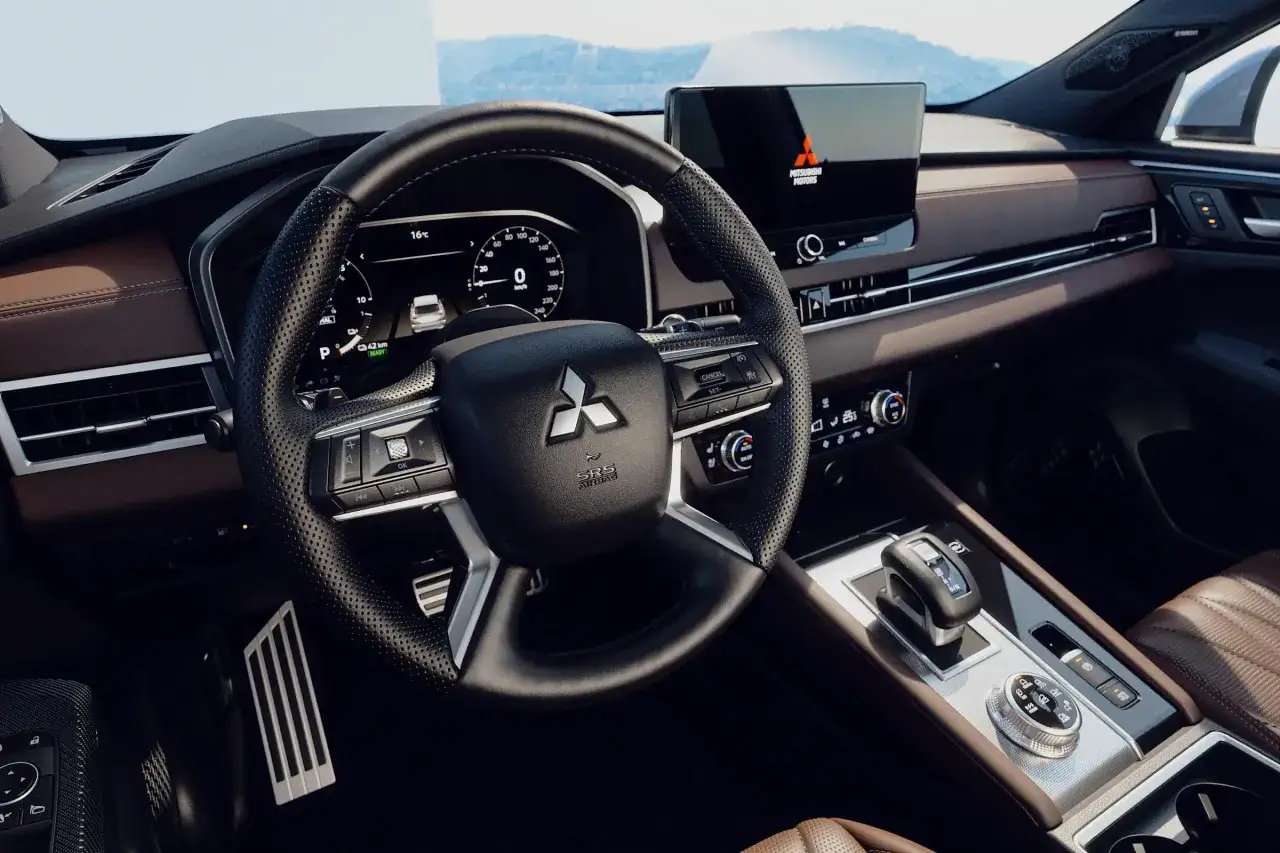 Wnętrze Mitsubishi Outlander: kierownica, cyfrowy kokpit z prędkościomierzem i ekranem multimedialnym, dźwignia zmiany biegów. Dane techniczne mitsubishi outlander.