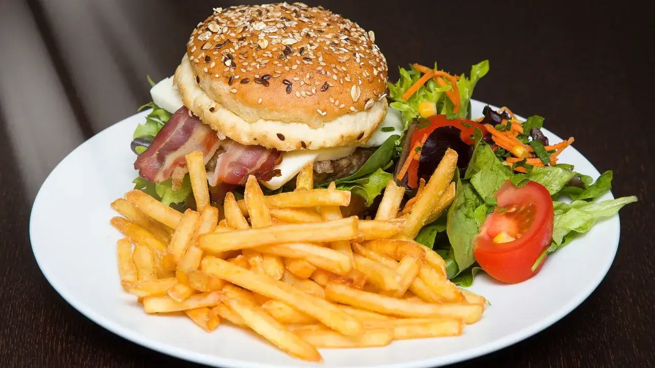 Hamburger in padella con patatine fritte croccanti e un'insalata fresca.