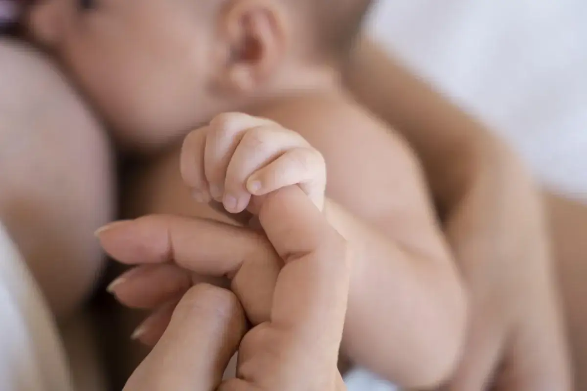Dłoń dziecka ściska palec matki. Ten gest może symbolizować głębokie więzi, ale też nierozwiązane mommy issues u kobiet, szukających w partnerach tej pierwszej, bezpiecznej miłości.