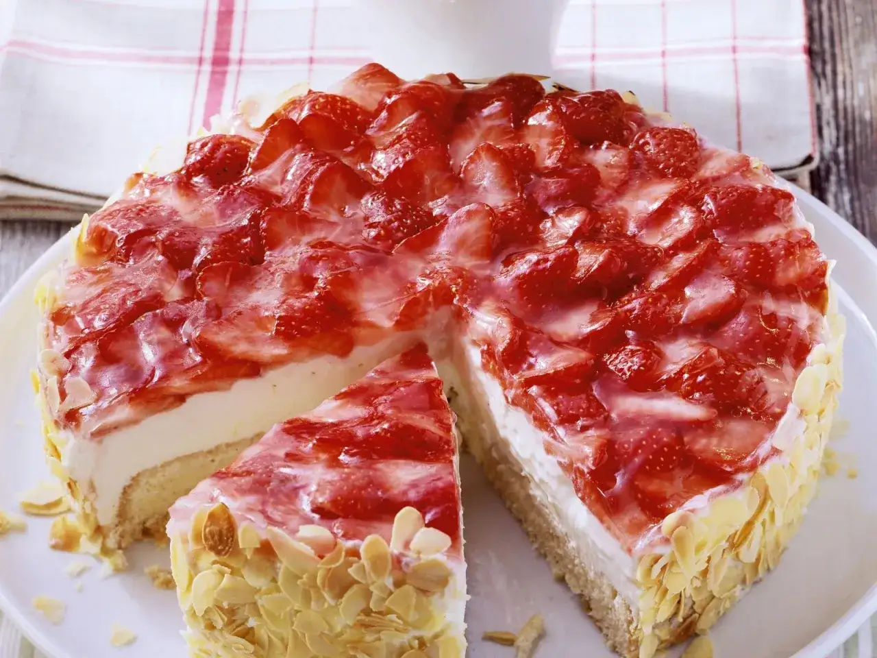 Eine einfache Torte mit frischen Erdbeeren und einer cremigen F&uuml;llung, umh&uuml;llt von ger&ouml;steten Mandelbl&auml;ttchen. Ein Genuss f&uuml;r jeden Anlass.