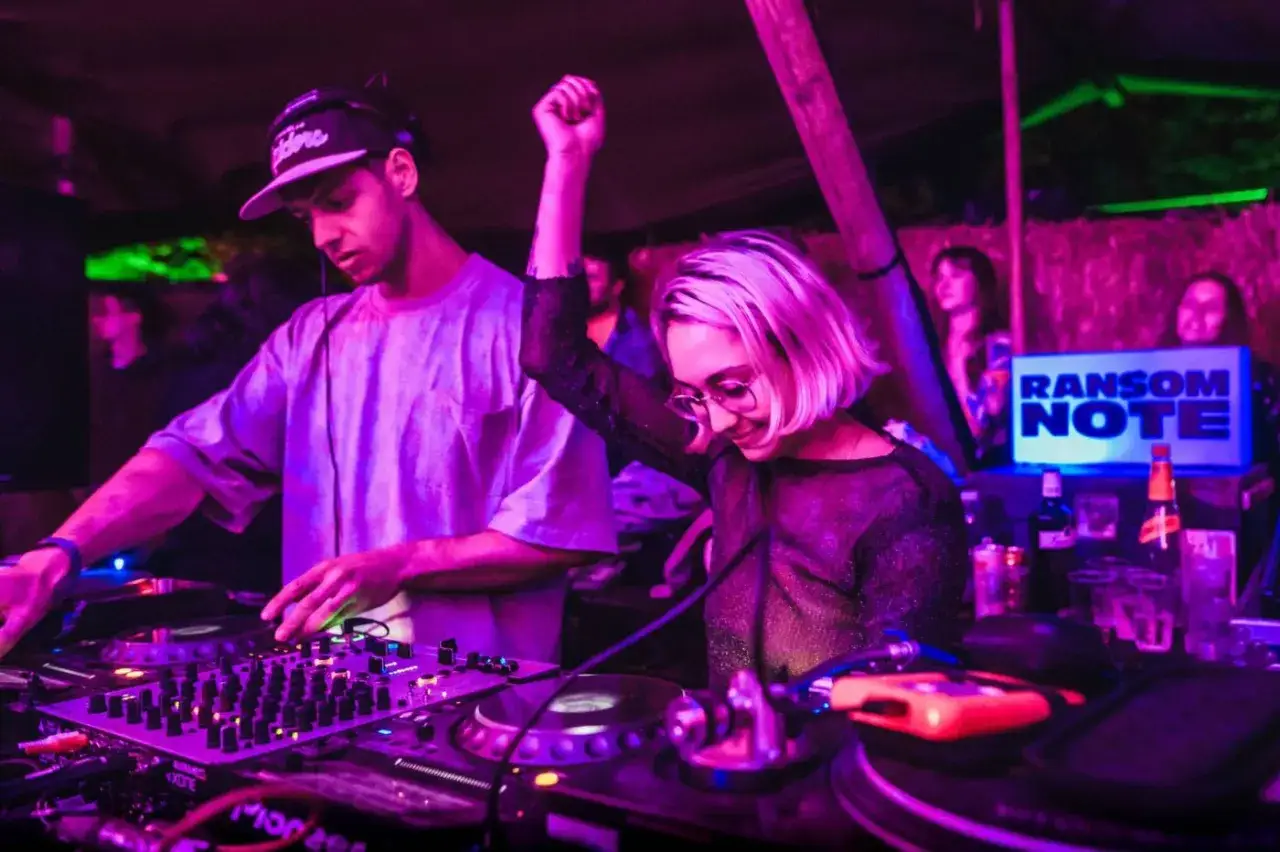 DJ che mixano musica in un locale notturno, creando un'atmosfera vibrante. Il b2b significato dj è la collaborazione tra artisti.