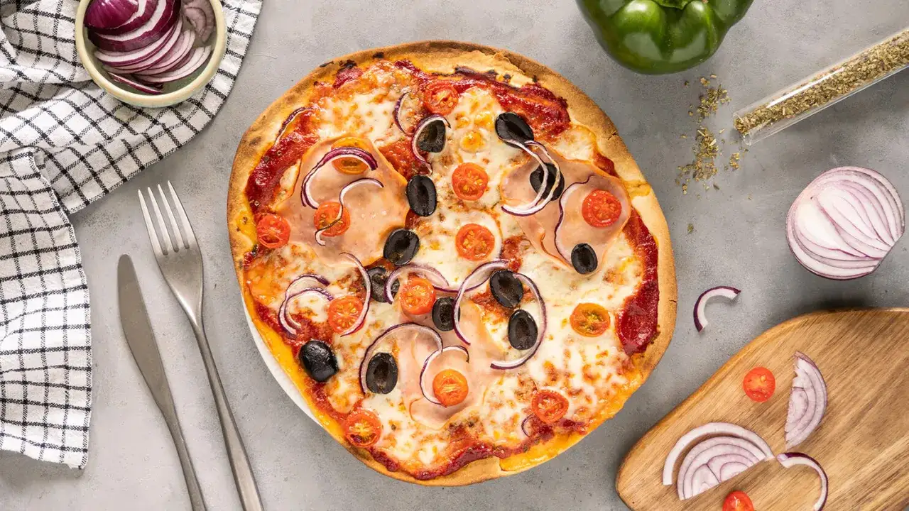 Pyszna pizza na gotowym spodzie z szynką, oliwkami, pomidorkami i czerwoną cebulą. Idealna na szybki obiad.
