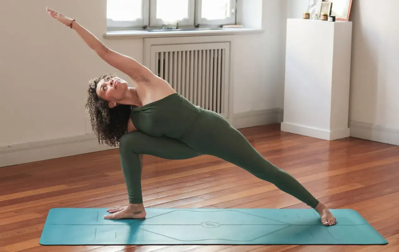 Mujer en Utthita Parsvakonasana, postura de yoga que expande el costado y fortalece las piernas.