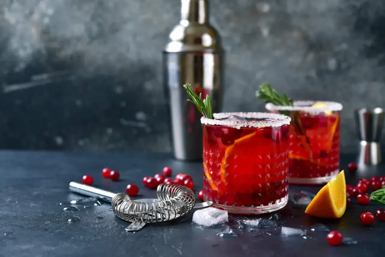 Eleganckie drinki na wesele z żurawiną i pomarańczą, ozdobione rozmarynem. Idealne na toast!