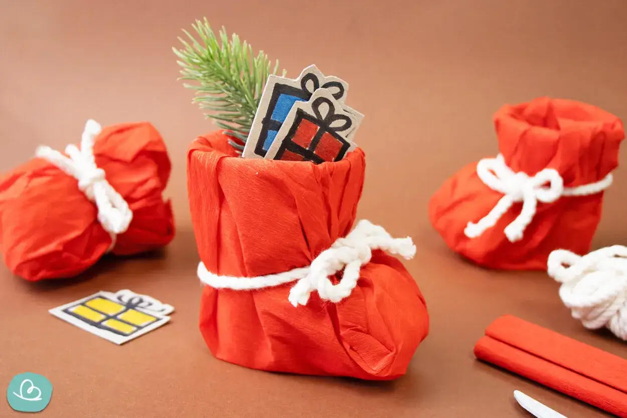 Kreative Weihnachtssocken aus gefaltetem Papier, gefüllt mit Geschenken und Tannenzweigen. Eine tolle Idee für Geld falten Socke.