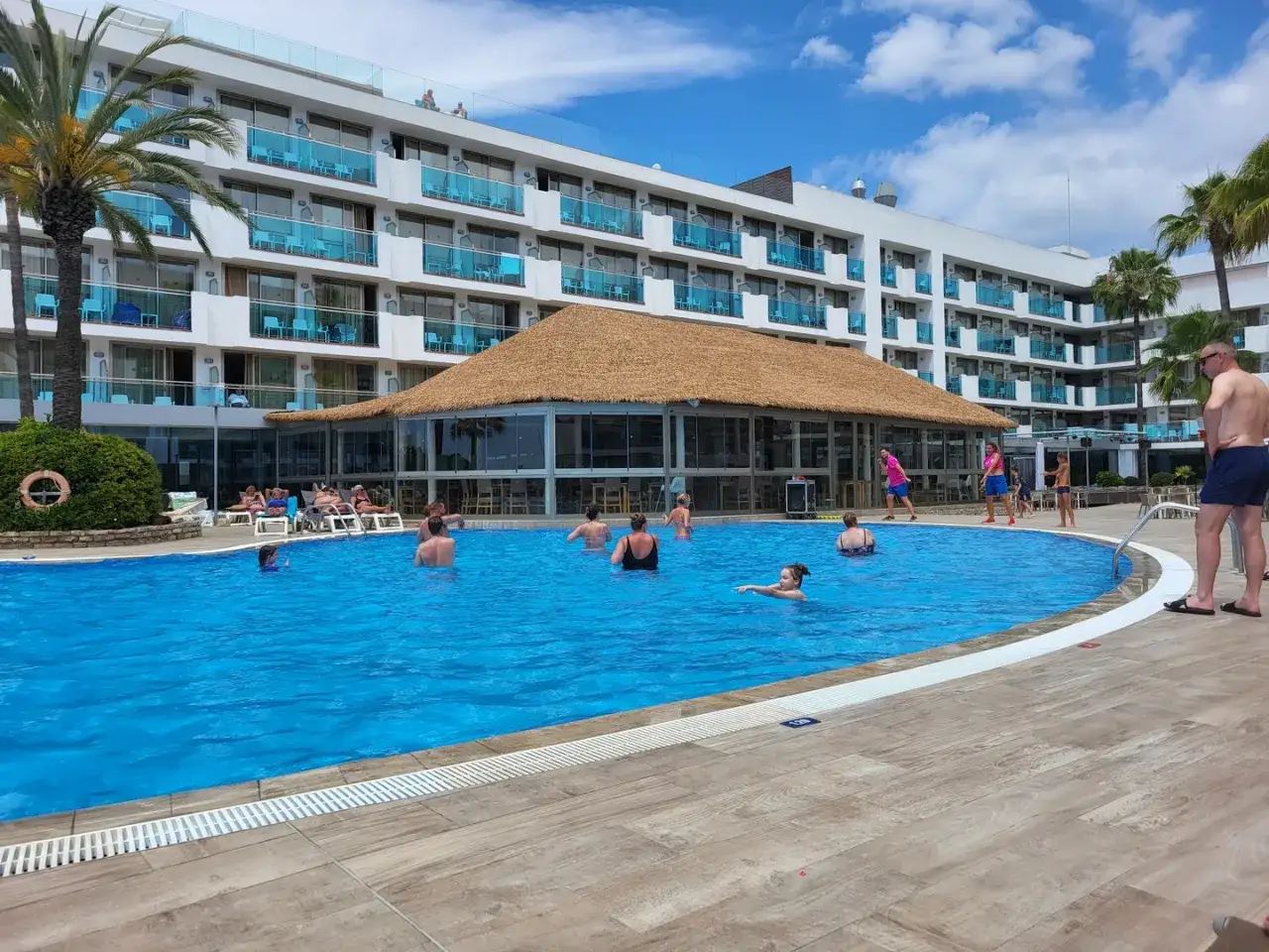 Relaks przy basenie w hotelu all inclusive soft. Ludzie pływają i odpoczywają w słoneczny dzień.