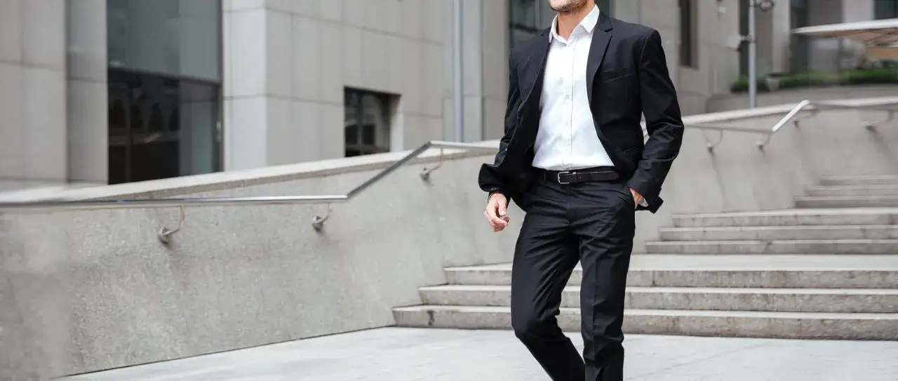 Man i kostym utan slips går nerför trappor. En modern och stilren look för affärsmannen.