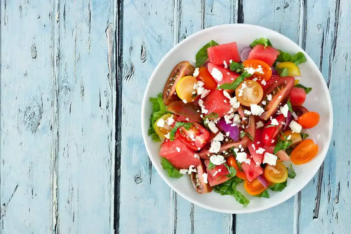 Insalata colorata con anguria, pomodori, cipolla rossa e feta. Perfetta per piatti freddi veloci e rinfrescanti.