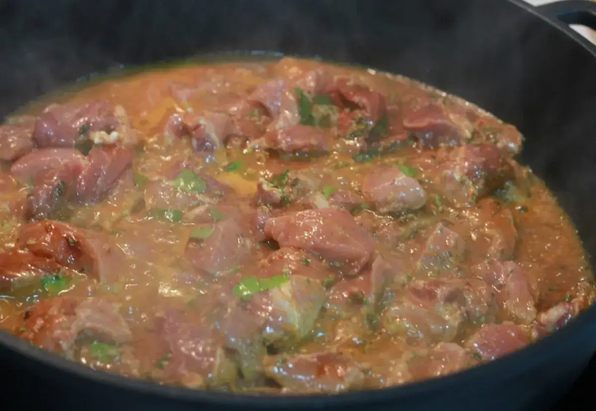 Sabrosa carne de raxo gallego cocin&aacute;ndose en una sart&eacute;n con una salsa dorada y especias.