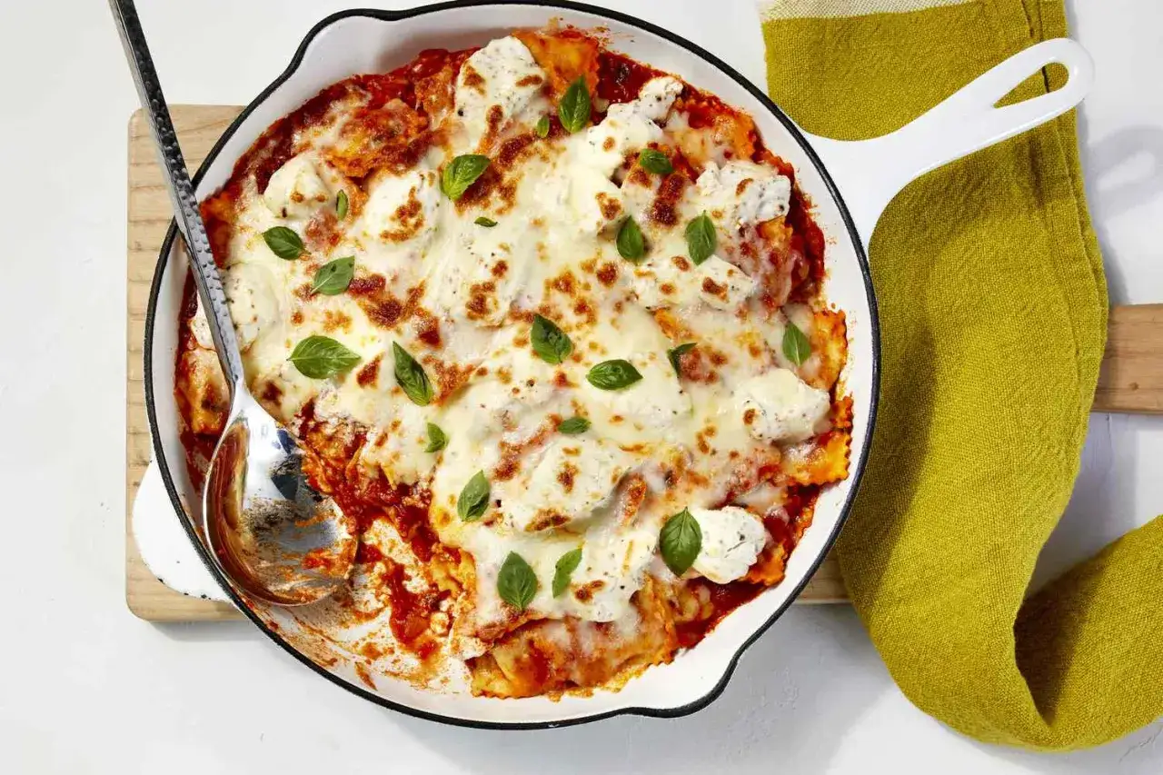 Zapiekane ravioli w sosie pomidorowym, pokryte ciągnącym się serem i listkami bazylii. Idealna szybka kolacja gotowa do podania.