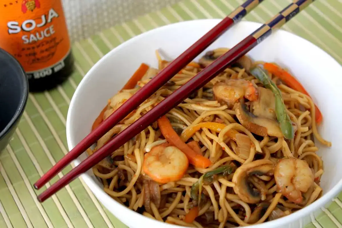 Deliciosos fideos de arroz con gambas, champiñones y verduras, listos para disfrutar con palillos.