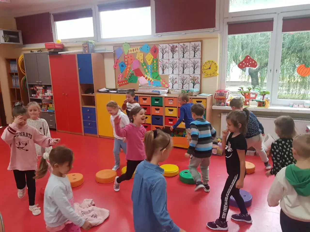 Dzieci w zerówce bawią się wesoło, nie zastanawiając się, ile godzin w zerówce minęło. Radość i ruch wypełniają salę.