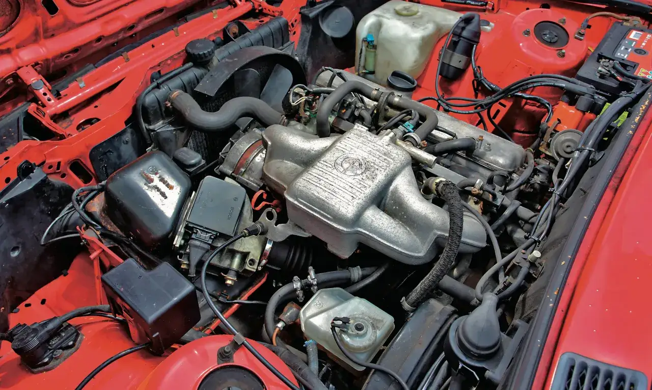 Silniki BMW E30, widok komory silnika z czerwonym lakierem. Widoczne elementy układu chłodzenia, zapłonowego i paliwowego.