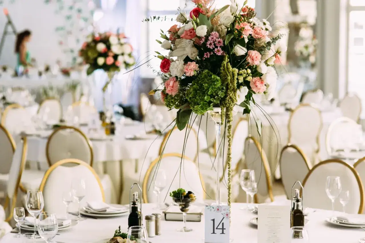 Elegancka sala weselna z bukietem kwiatów na stole. Sprawdź, jaka wedding planner cena jest najlepsza dla Twojego wymarzonego przyjęcia.