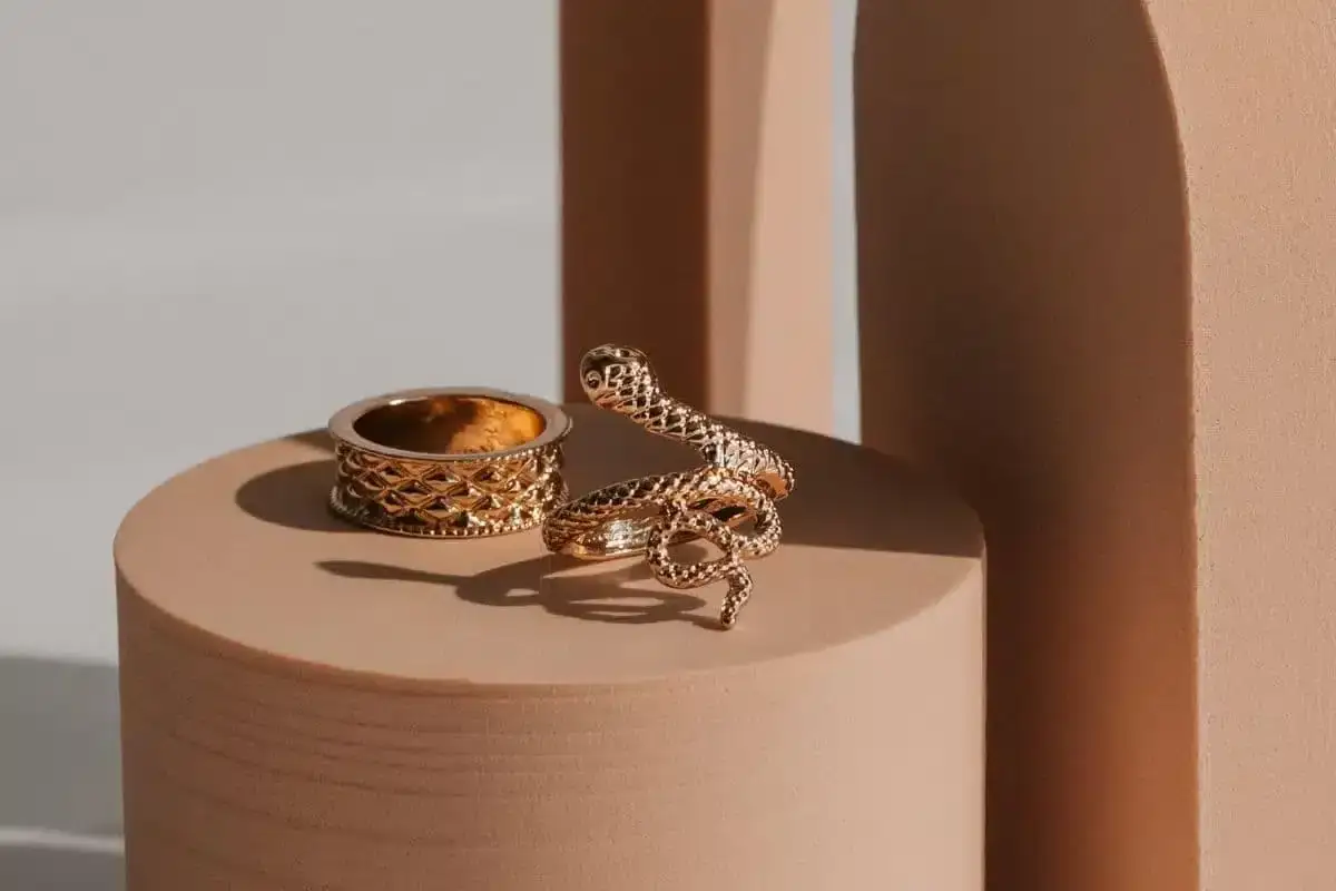 Anelli dorati, uno a serpente avvolto, l'altro con texture a rombi. Un'idea per un progetto gioielleria audace e raffinato.