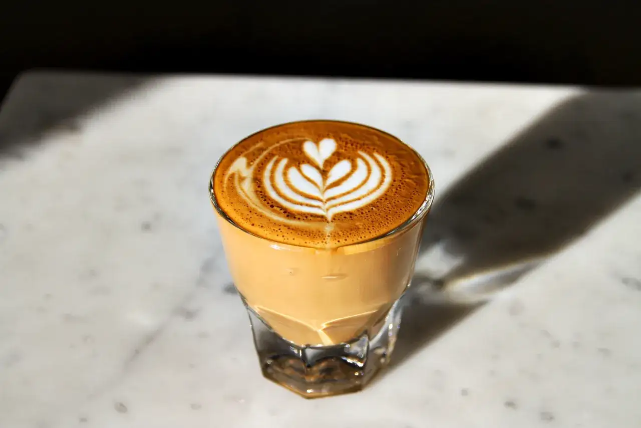 Perfekte Cortado Zubereitung mit kunstvollem Latte Art Muster auf cremigem Milchschaum.