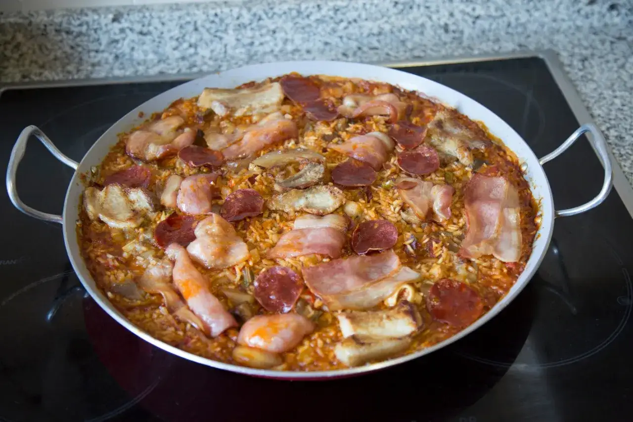 Un delicioso arroz a la zamorana, con trozos de chorizo, panceta y carne, listo para servir en su paellera.