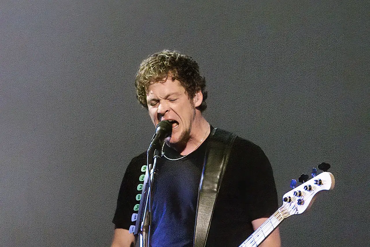 Jason Newsted, wokalista i basista, śpiewa do mikrofonu, grając na gitarze basowej.