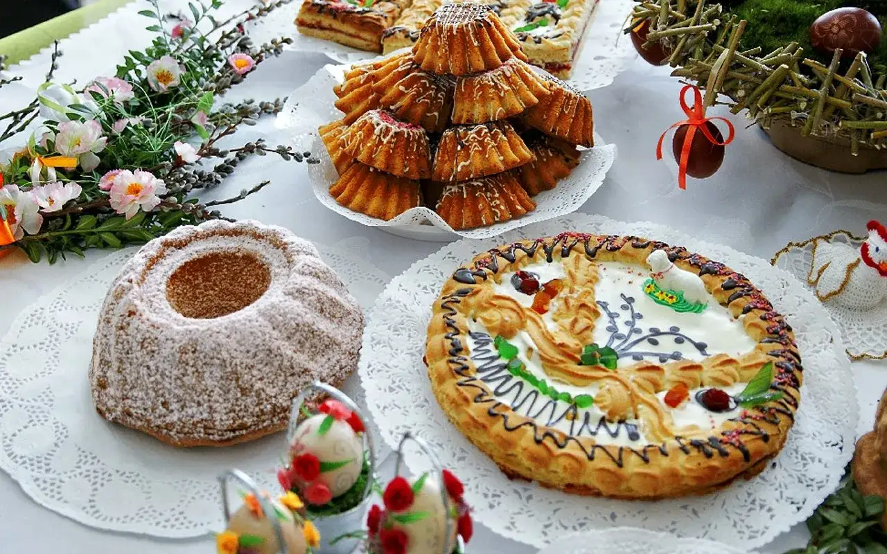 Wielkanocne ciasta i babeczki, ozdobione barankiem i pisankami. Tradycyjnie, czy w Wielką Sobotę można jeść mięso? Nie widać go na stole.