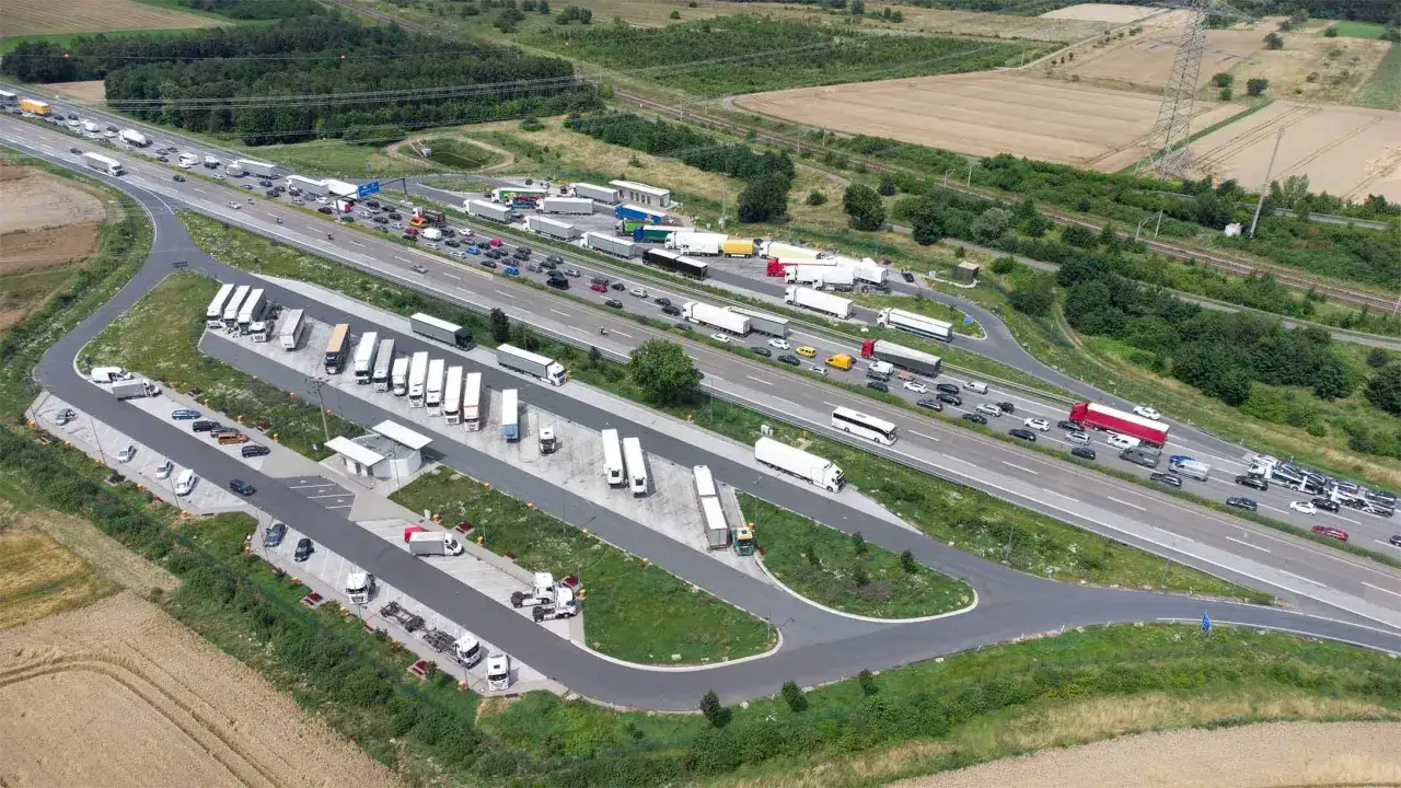 Vista a&eacute;rea de un &aacute;rea de **parking camiones** con muchos veh&iacute;culos estacionados y tr&aacute;fico en la autopista.