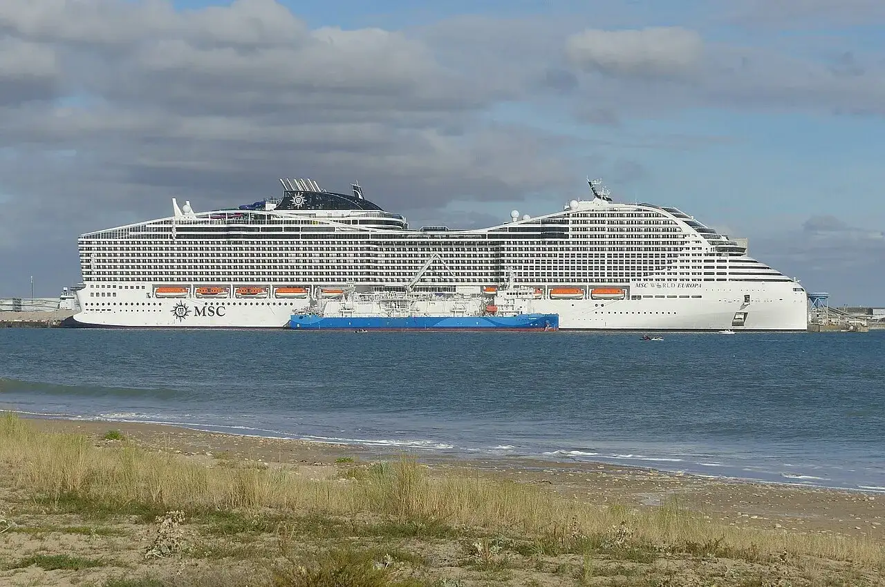 MSC World Europa, un gigante dei mari, mostra la sua impressionante altezza accanto a una nave cisterna blu.