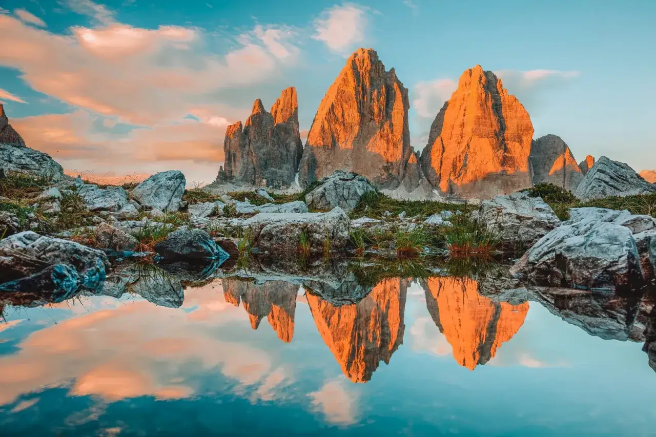 Sonnenuntergang in den Dolomiten. Ein perfekter Moment für Backpacking in Italien, mit den Drei Zinnen, die sich in einem Bergsee spiegeln.