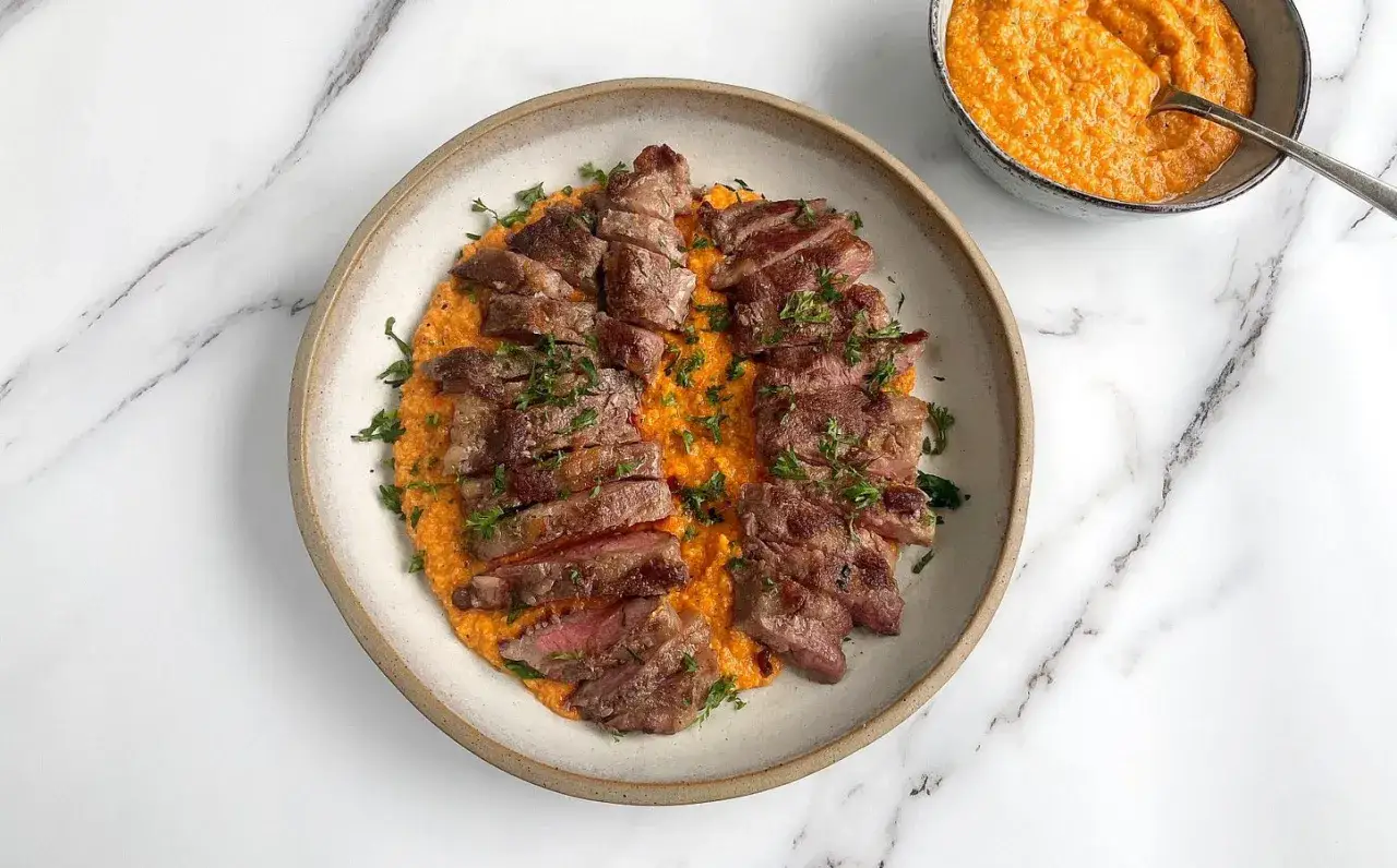 Pluma de porc recette : fines tranches de viande de porc grillée, servies sur une purée orangée et garnies de persil frais.