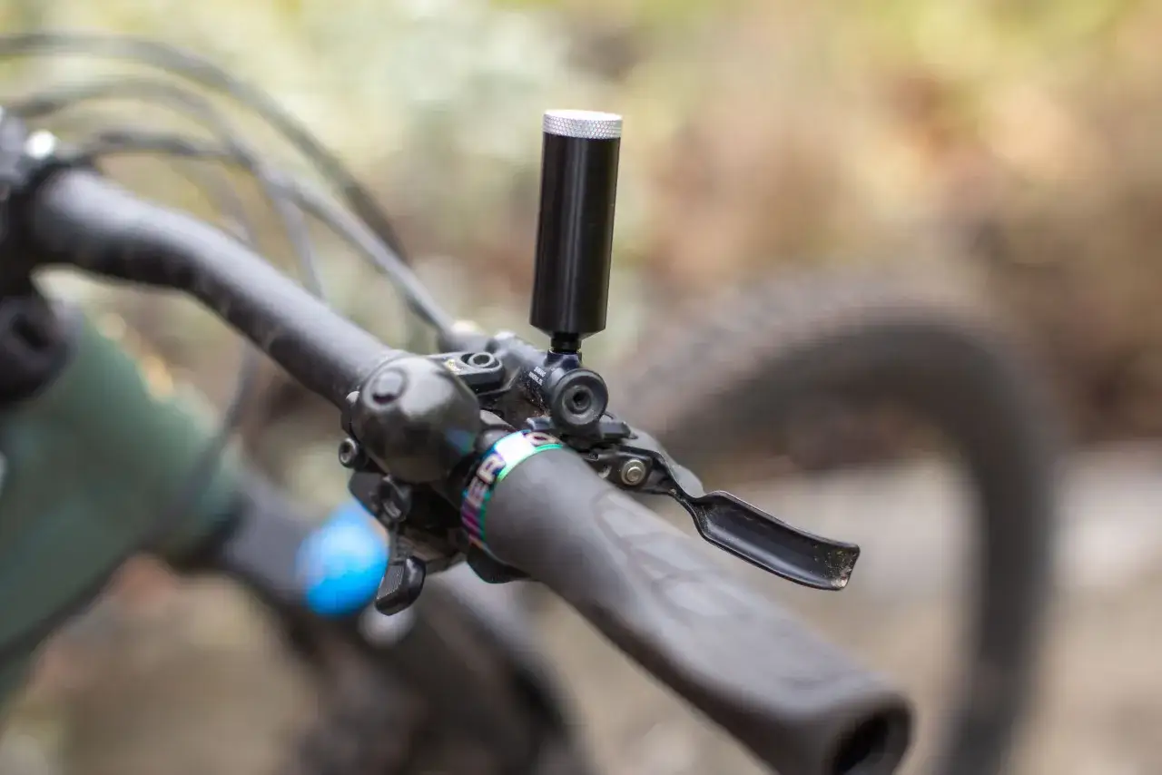 Close-up of a bicycle handlebar with a brake lever and a bleed kit attached. This setup is crucial for maintaining optimal brake performance, ensuring the correct brake bleed order.