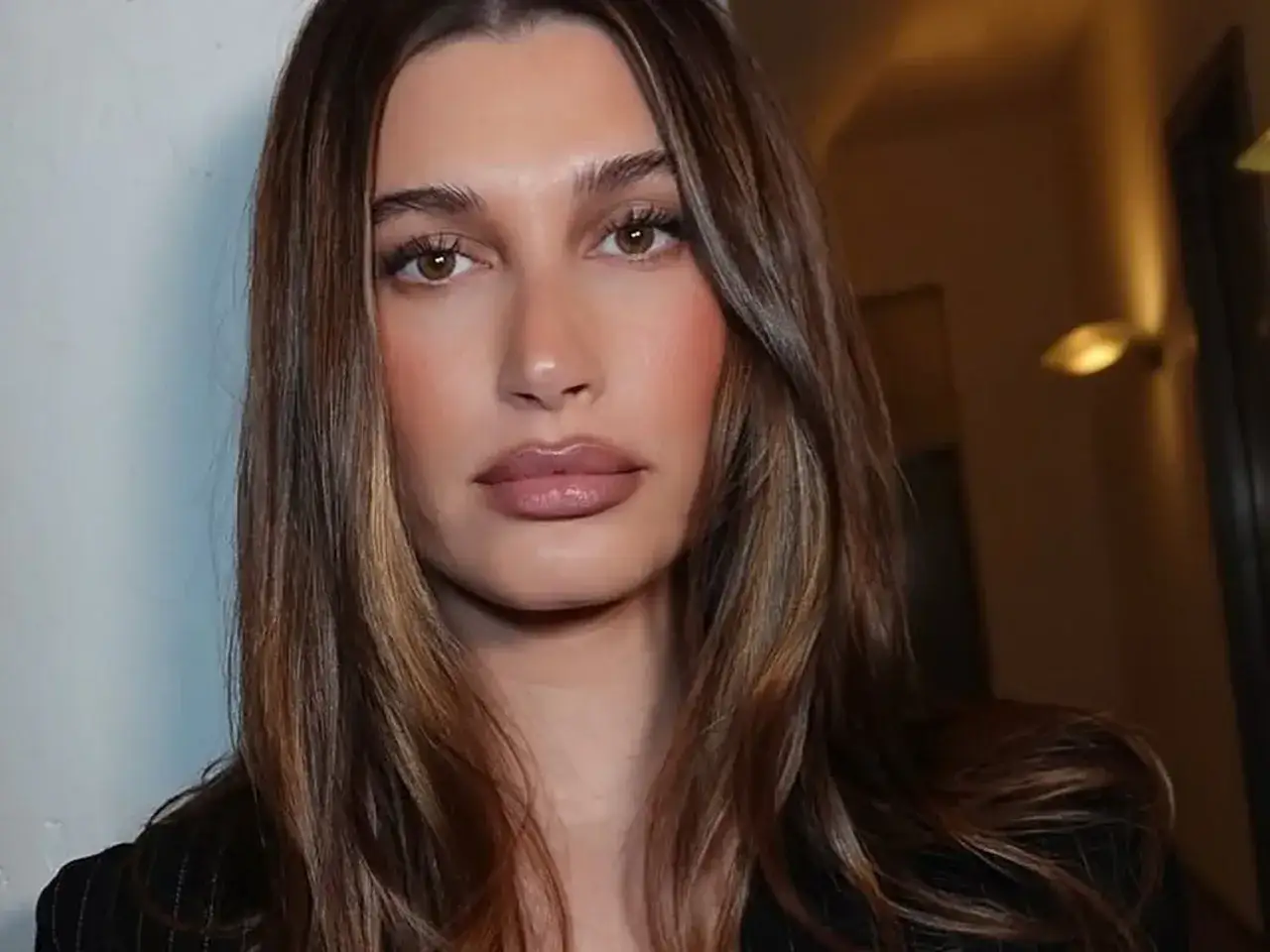 En kvinna med slingat brunt h&aring;r och en mjuk makeup-look.