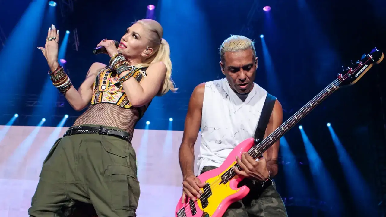 Gwen Stefani singt mit Mikrofon, w&auml;hrend ein Bassist auf einer pinken E-Gitarre spielt.