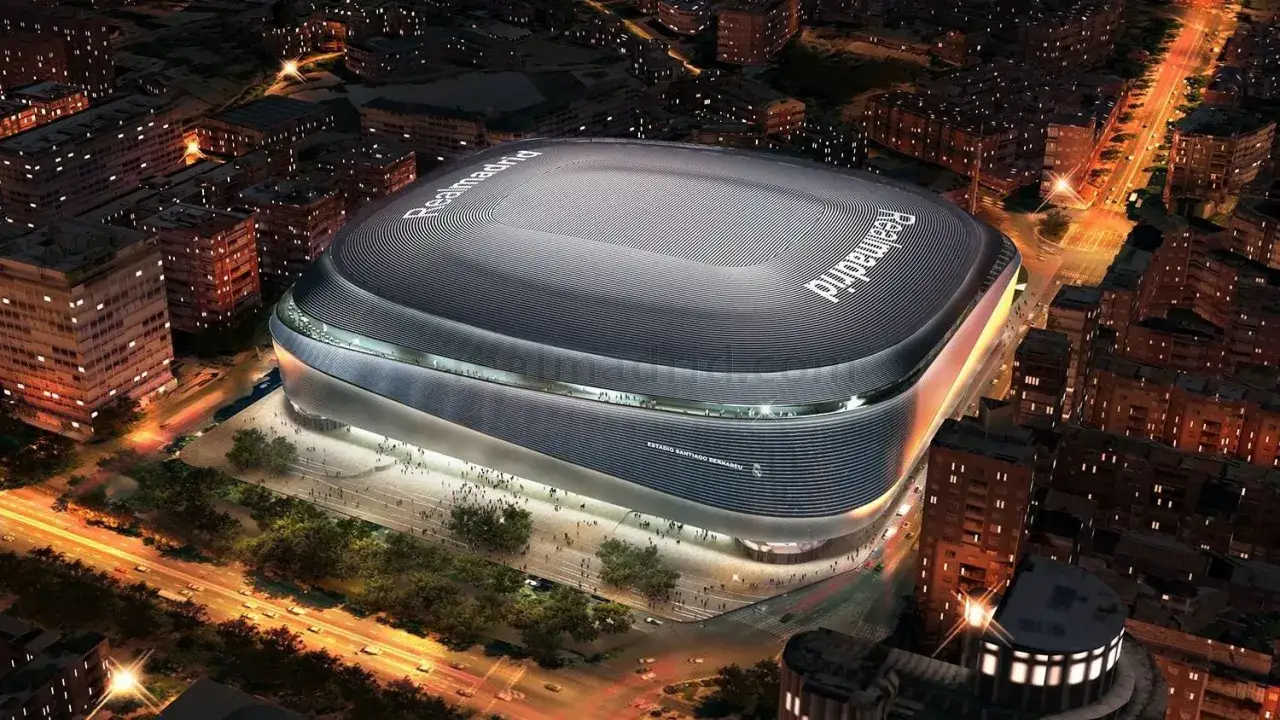 Nowoczesny stadion Realu Madryt, Santiago Bernabéu, nocą, otoczony miejską zabudową i oświetlonymi ulicami.