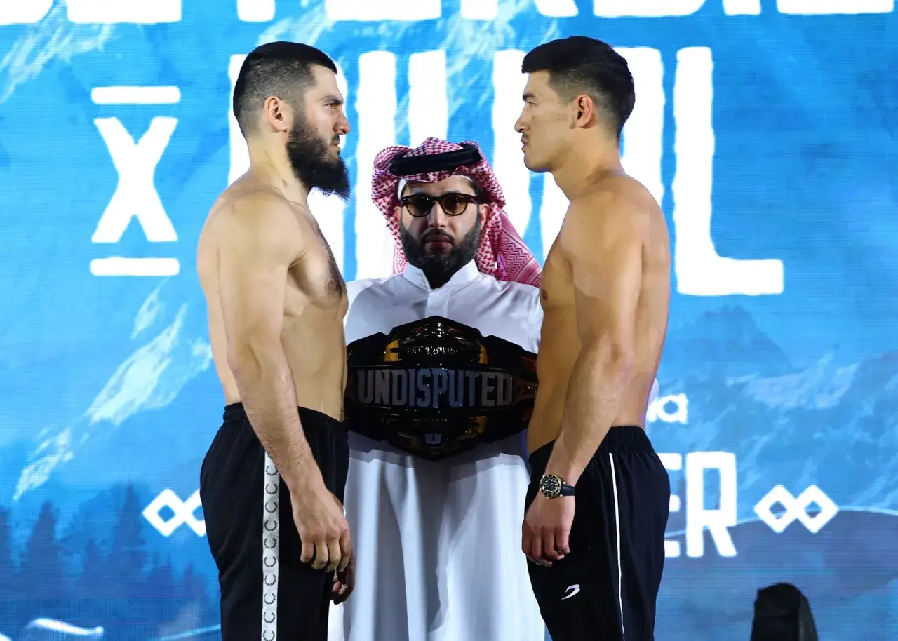 Two boxers face off, a championship belt held between them. This is the beterbiev weight class showdown.